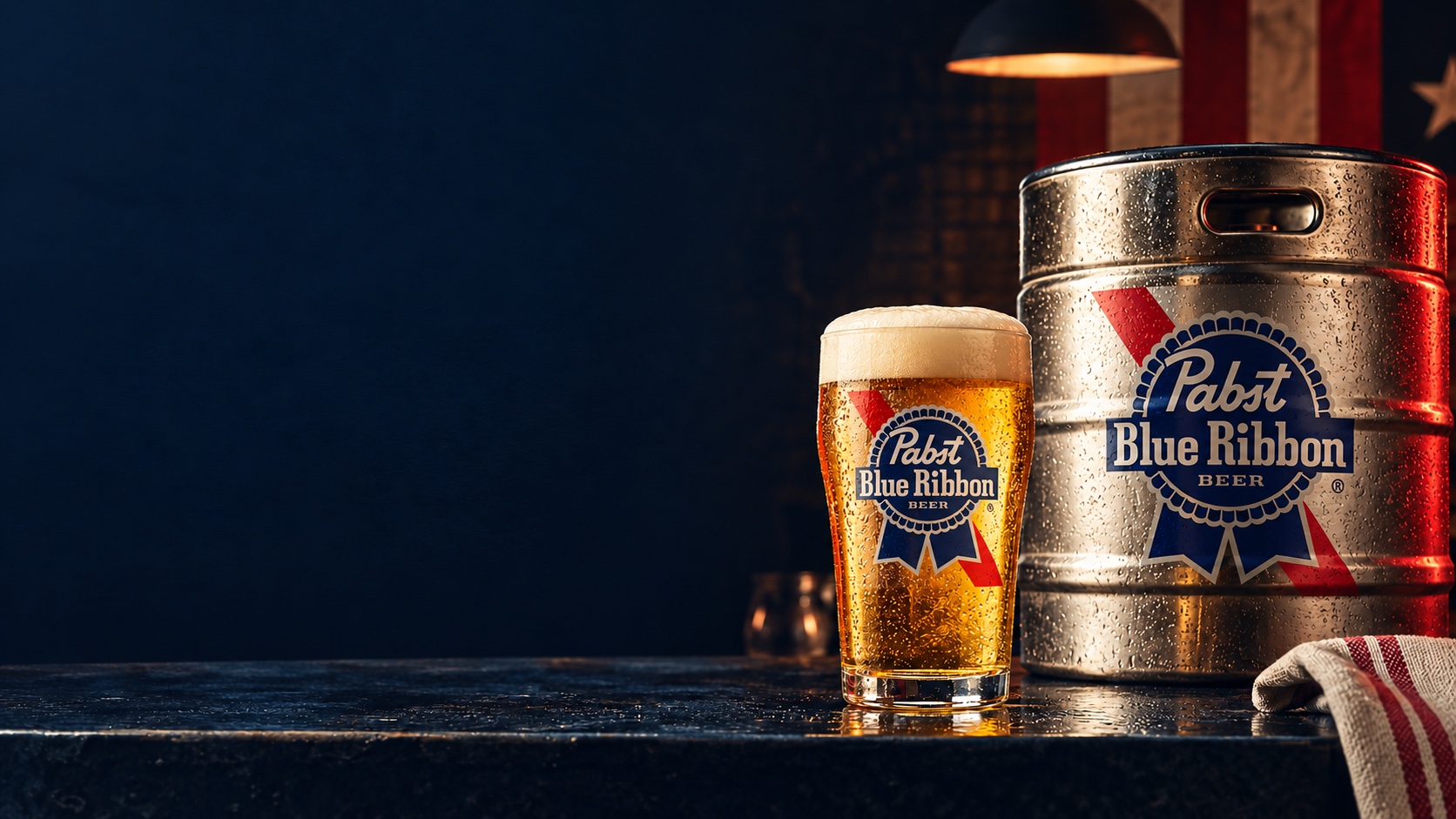 Copo de chopp Pabst Blue Ribbon ao lado de barril com o mesmo logo